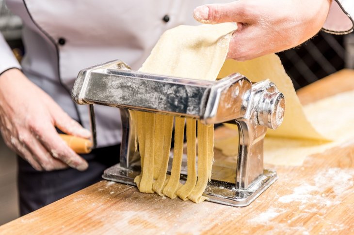 Kok der laver pasta med en pastamaskine